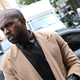An image of Kanye West in a camel colored coat looking to the side.